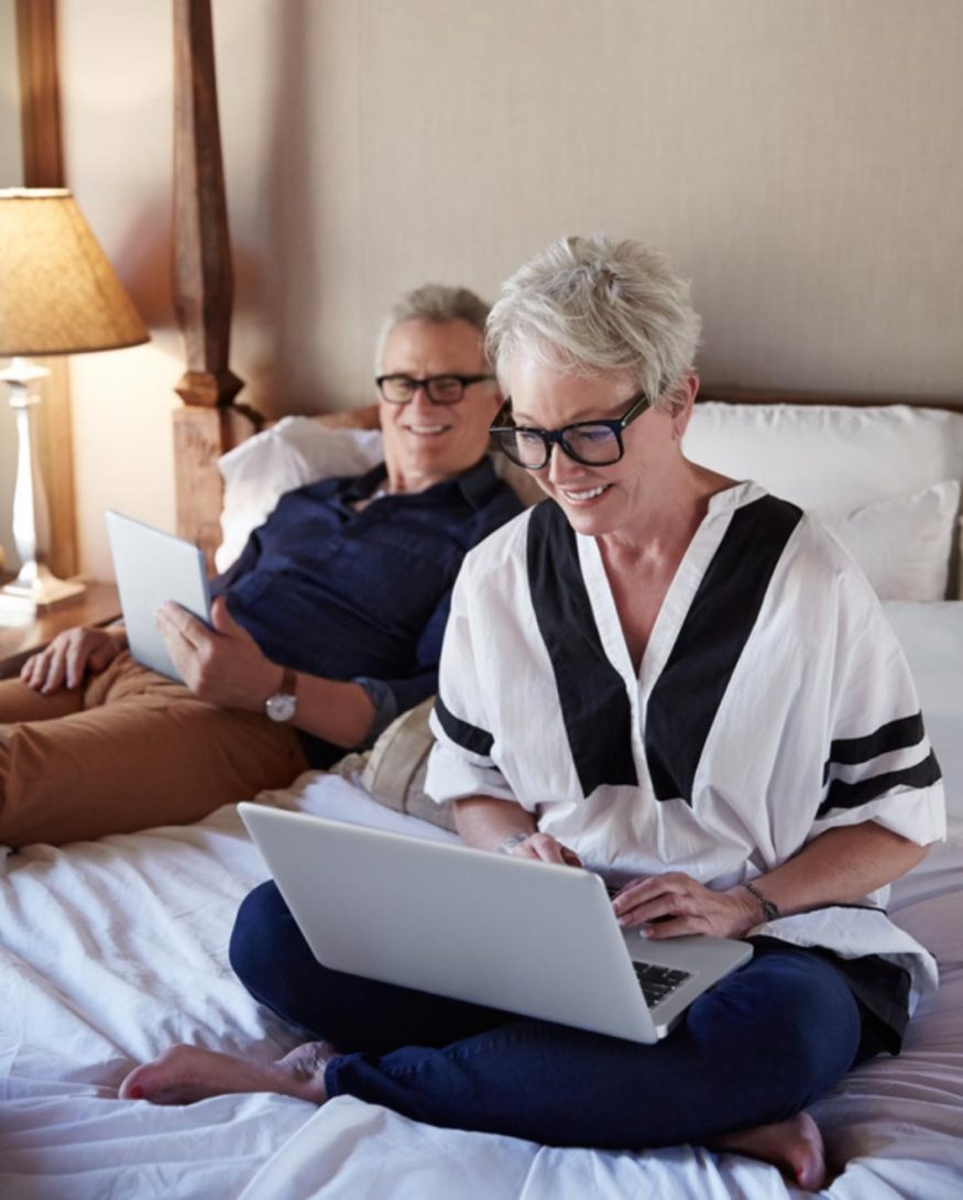 Couple On Computers In Bed